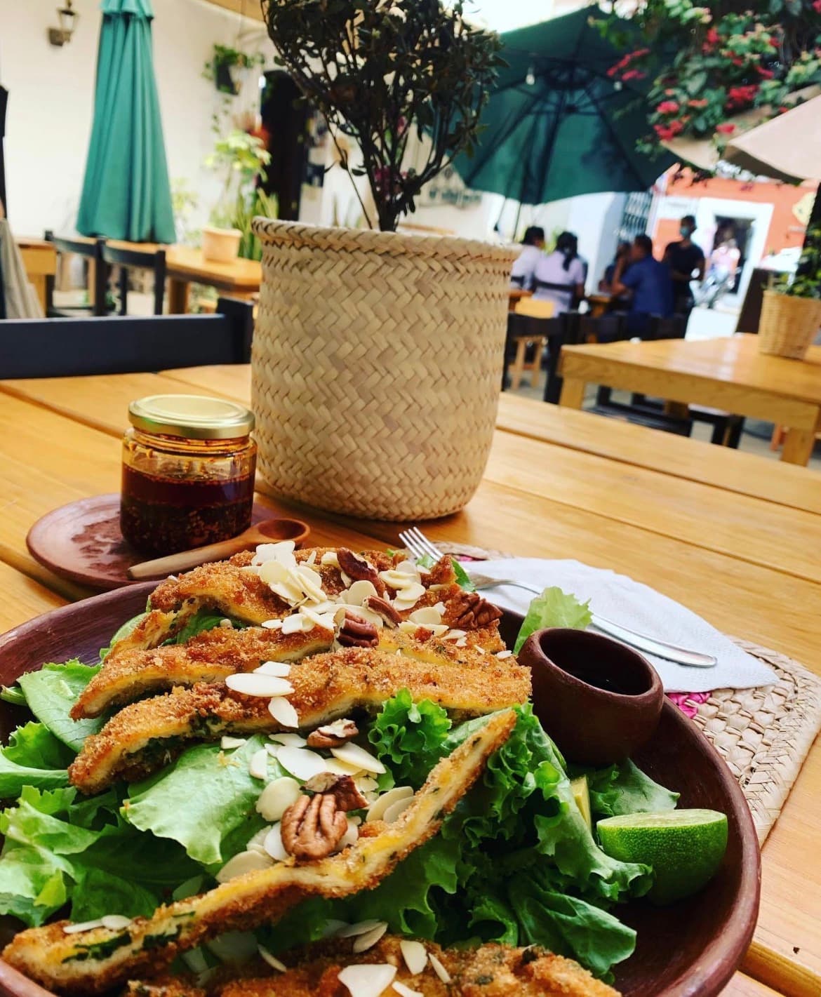 Plato con tiras empanizadas sobre ensalada verde, servido en la terraza