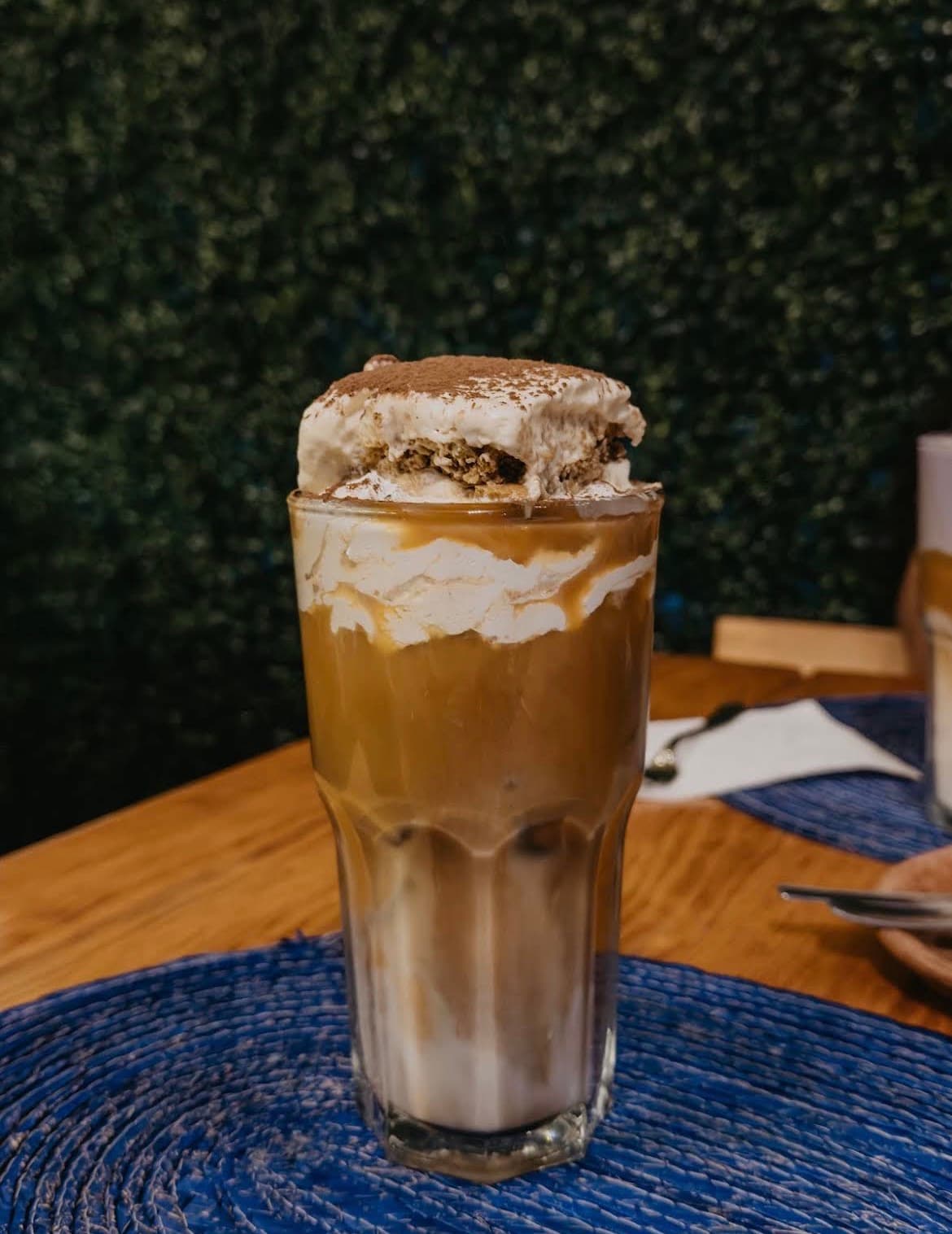 Latte de Tiramisú con crema batida y cacao espolvoreado en vaso alto