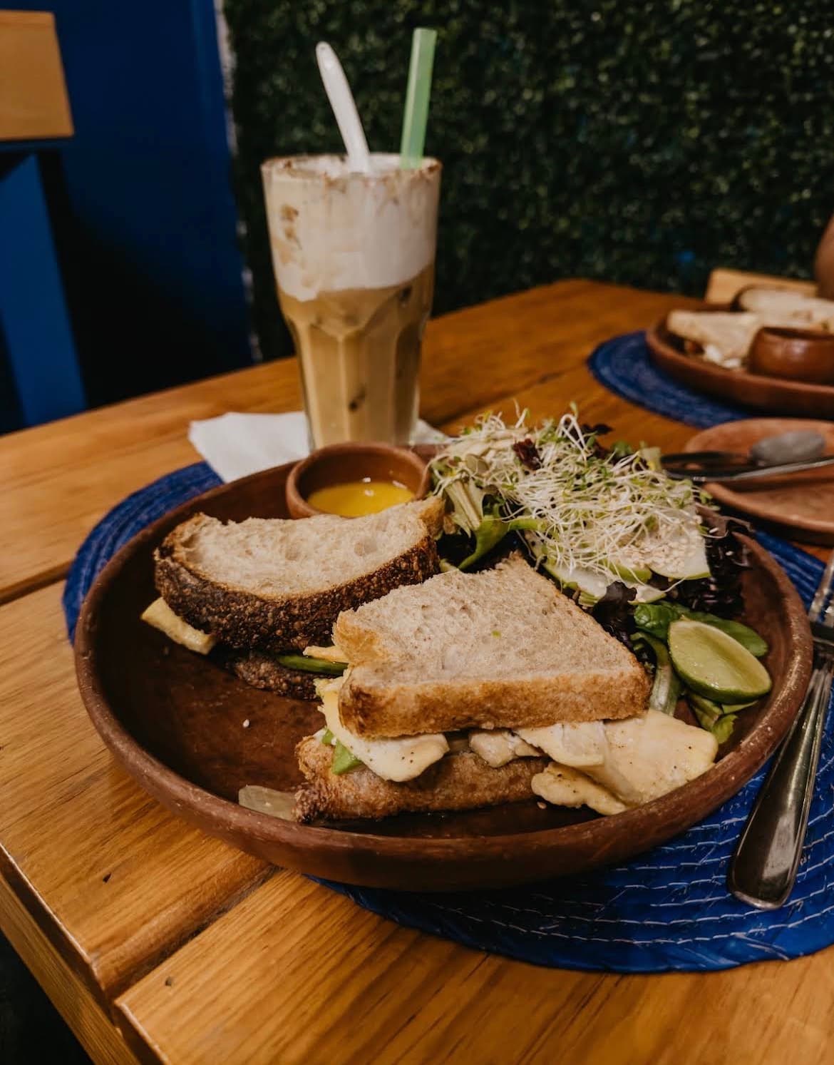 Sándwich de pechuga de pollo asada con ensalada y bebida fría de fondo